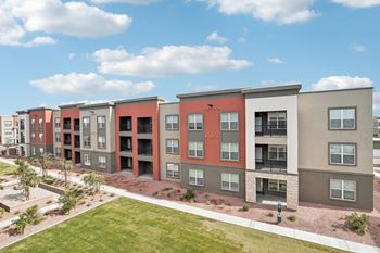An apartment building with a green lawn and a blue sky